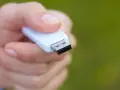 Dłoń trzyma biały pendrive, gotowy do formatowania NTFS.
