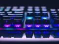 Zbliżenie na klawiaturę gamingową z kolorowym podświetleniem RGB. Widoczne klawisze Shift, Ctrl i strzałki. Różne rodzaje klawiatur oferują unikalne wrażenia.