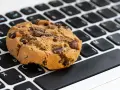 Ciasteczko z kawałkami czekolady leży na klawiaturze laptopa. Czy to są ciasteczka, które śledzą Twoje kliknięcia?