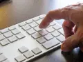 Dłoń naciska klawisz 8 na klawiaturze. W tle widać klawisz Windows.