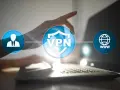 Dłoń dotyka ikony VPN, symbolizującej bezpieczne połączenie z internetem przez wifi.