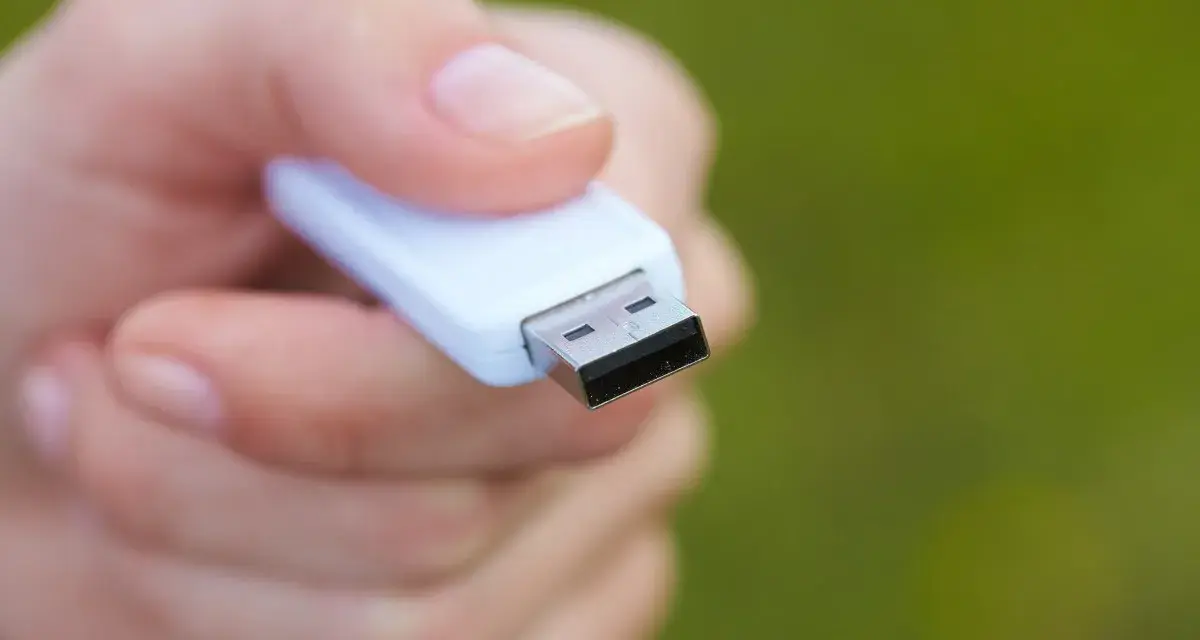 Dłoń trzyma biały pendrive, gotowy do formatowania NTFS.