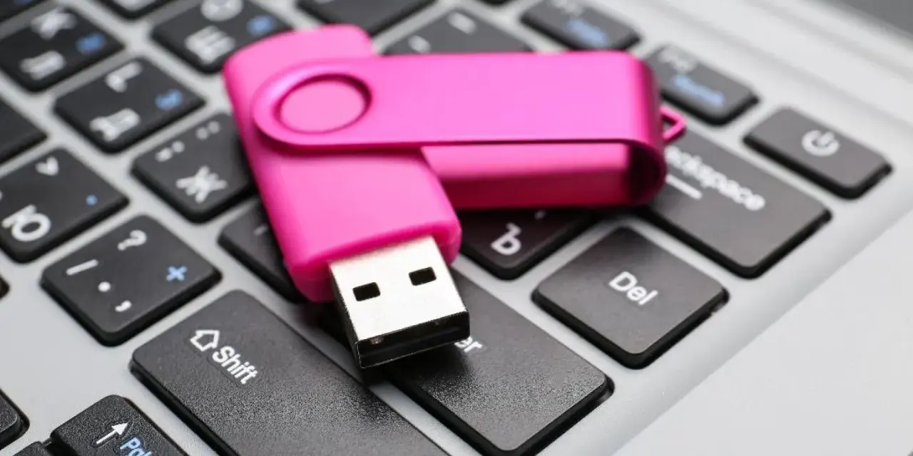 Różowy pendrive leży na klawiaturze, gotowy do pracy jak przenośny dysk twardy.