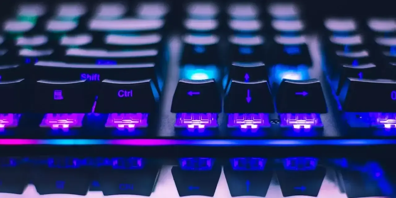 Zbliżenie na klawiaturę gamingową z kolorowym podświetleniem RGB. Widoczne klawisze Shift, Ctrl i strzałki. Różne rodzaje klawiatur oferują unikalne wrażenia.