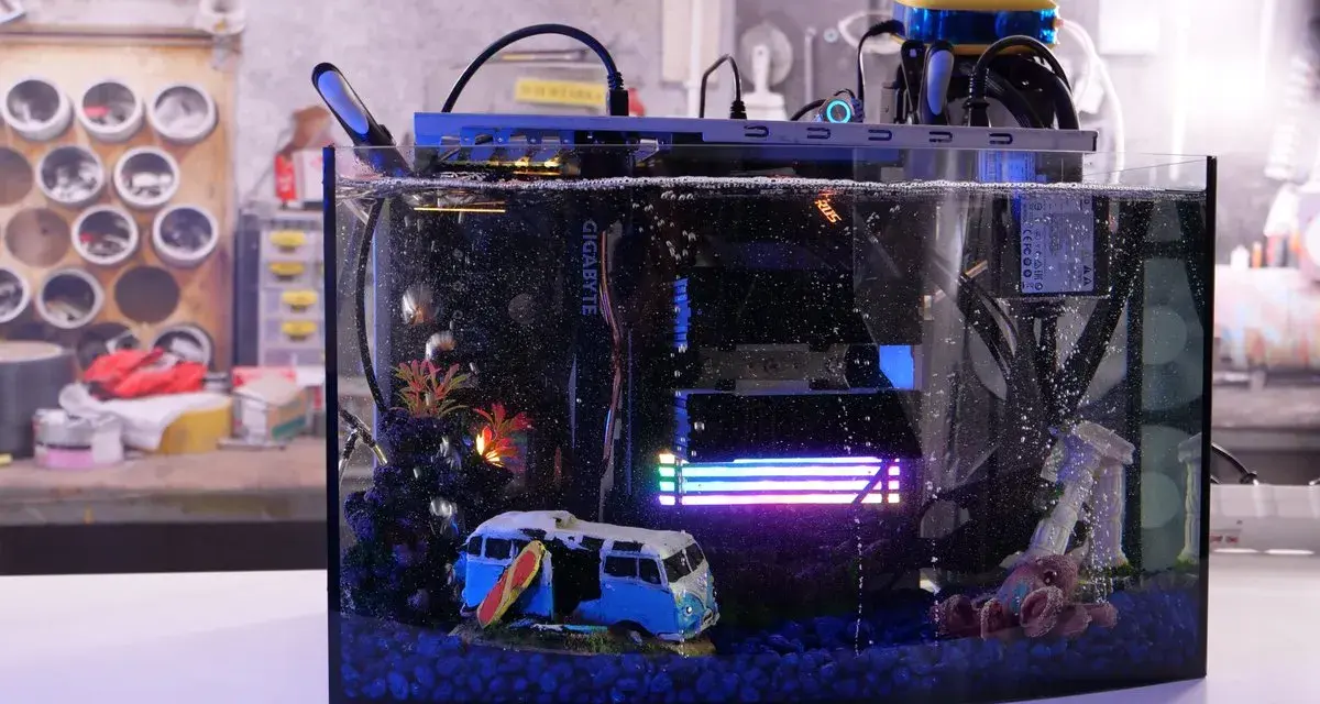 Komputer w akwarium z chłodzeniem cieczą, zanurzony w oleju mineralnym. W środku miniaturowy kamper i surfer.