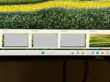 Widok czterech pulpitów Windows 10, z czego trzy są szare, a czwarty pokazuje kolorowy krajobraz. Pasek zadań z wyszukiwarką i ikonami.