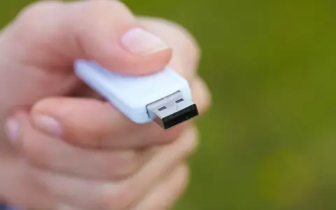 Dłoń trzyma biały pendrive, gotowy do formatowania NTFS.