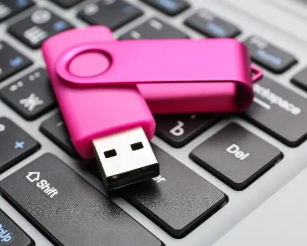 Różowy pendrive leży na klawiaturze, gotowy do pracy jak przenośny dysk twardy.
