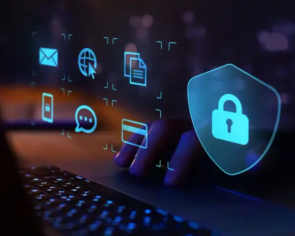 Dłoń na klawiaturze, nad nią ikony symbolizujące dane i komunikację, a obok tarcza z kłódką. Chroń się przed wirusami w internecie.