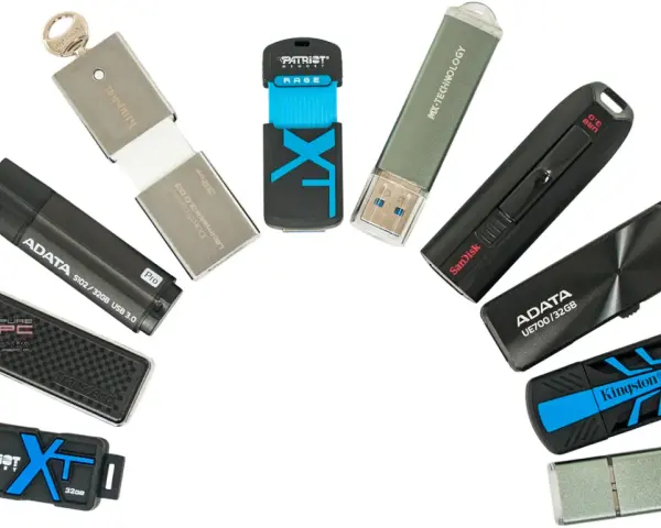 Różne modele pendrive'ów, czyli przenośnych pamięci USB, ułożone w łuk. Widać marki Kingston, ADATA, SanDisk, Patriot, Transcend, MX-TECHNOLOGY.