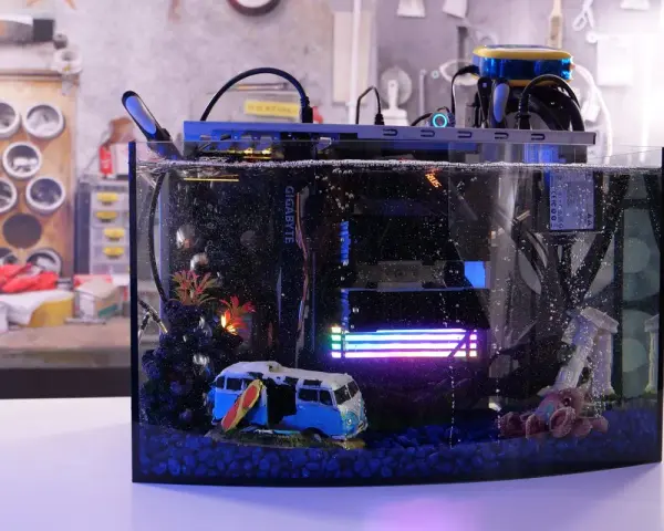 Komputer w akwarium z chłodzeniem cieczą, zanurzony w oleju mineralnym. W środku miniaturowy kamper i surfer.