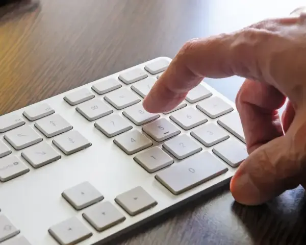 Dłoń naciska klawisz 8 na klawiaturze. W tle widać klawisz Windows.
