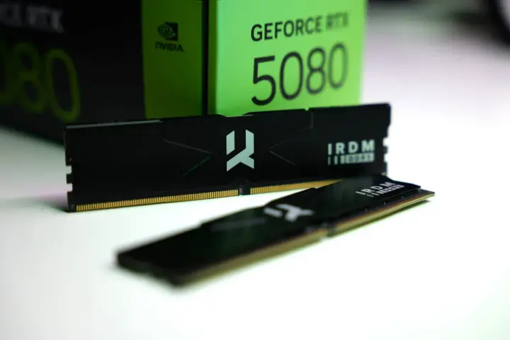 Dwa moduły pamięci RAM IRDM DDR5 leżą przed zielonym pudełkiem karty graficznej GeForce RTX 5080.