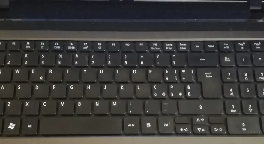 Klawiatura laptopa z włoskim układem klawiatury. Widoczne klawisze z literami, cyframi i symbolami, w tym € i accented vowels.