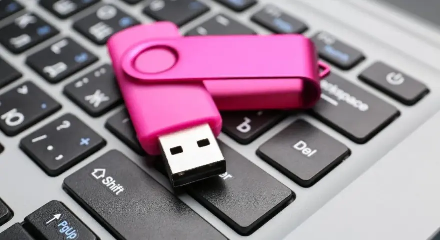 Różowy pendrive leży na klawiaturze, gotowy do pracy jak przenośny dysk twardy.