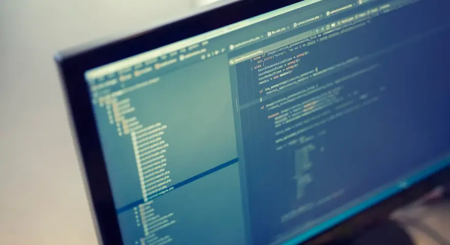 Programista pracuje nad kodem PHP. Format komputera pozwala na szybkie tworzenie i edycję skomplikowanych projektów.