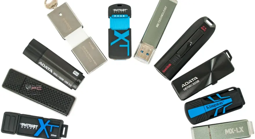 Różne modele pendrive'ów, czyli przenośnych pamięci USB, ułożone w łuk. Widać marki Kingston, ADATA, SanDisk, Patriot, Transcend, MX-TECHNOLOGY.