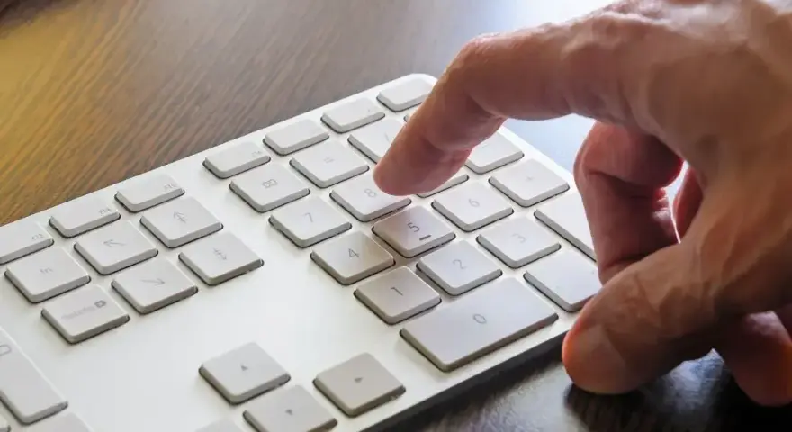 Dłoń naciska klawisz 8 na klawiaturze. W tle widać klawisz Windows.