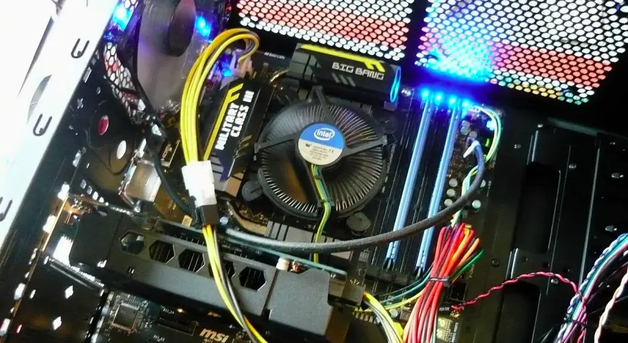 Wnętrze komputera z podświetlaną płytą główną MSI i wentylatorem Intel. Pokazuje, jak działa komputer, z widocznymi kablami i elementami.