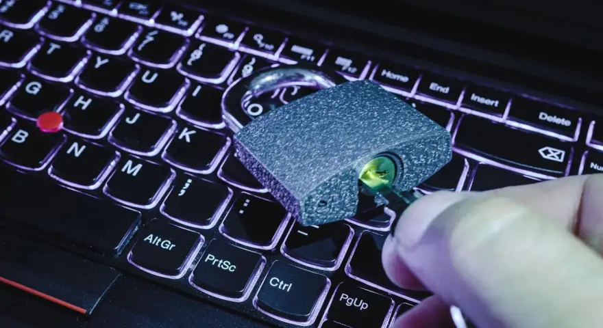 Klucz w zamku na klawiaturze laptopa. Symbolizuje to, jak sprawdzić czy plik ma wirusa i chronić dane.