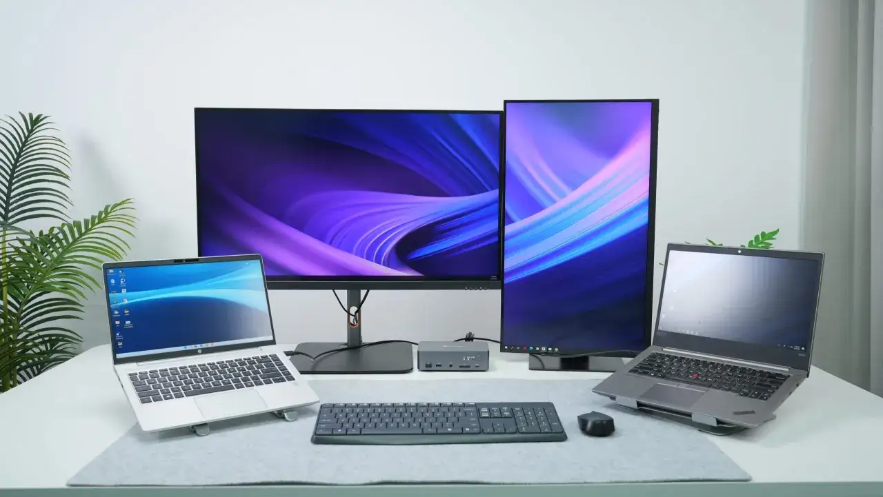 Dwa laptopy, dwa monitory z abstrakcyjnymi tapetami, klawiatura i mysz. Gotowe do pierwszego uruchomienia komputera i pracy.