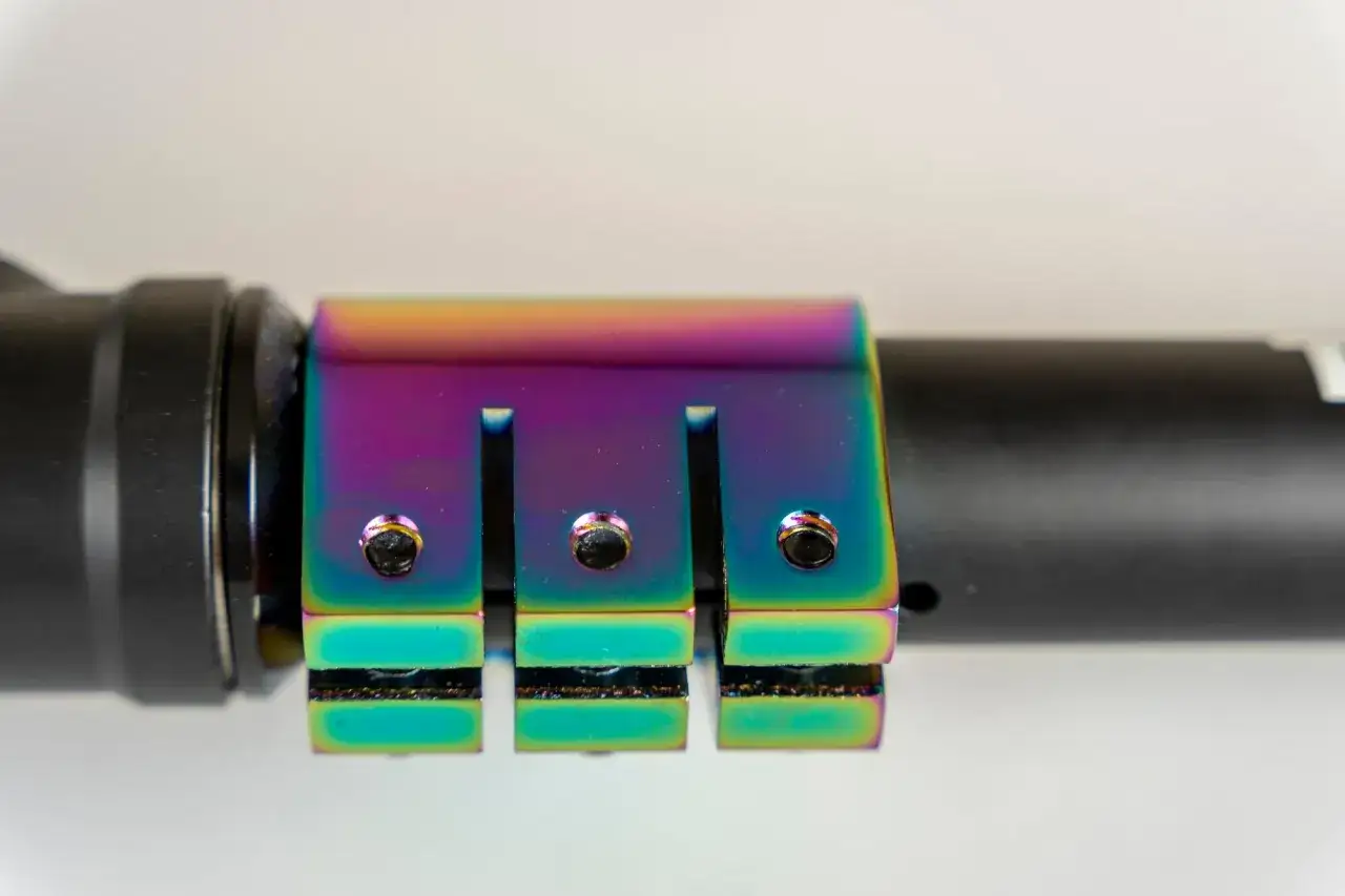 Tęczowy element mocowania, przypominający paletę ARGB vs RGB, z widocznymi śrubami.